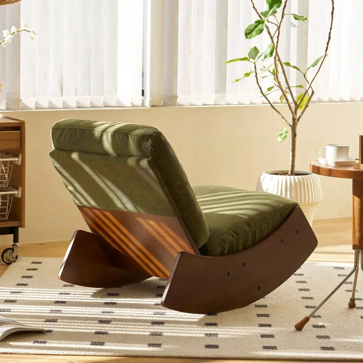 Green cushioned chair with wooden base in a room with a plant and desk.
