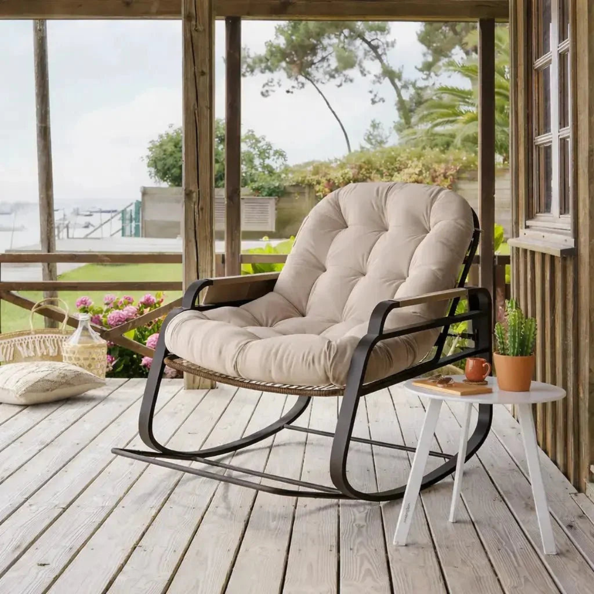 Beige cushioned rocking chair on a wooden deck with a view of greenery outside.