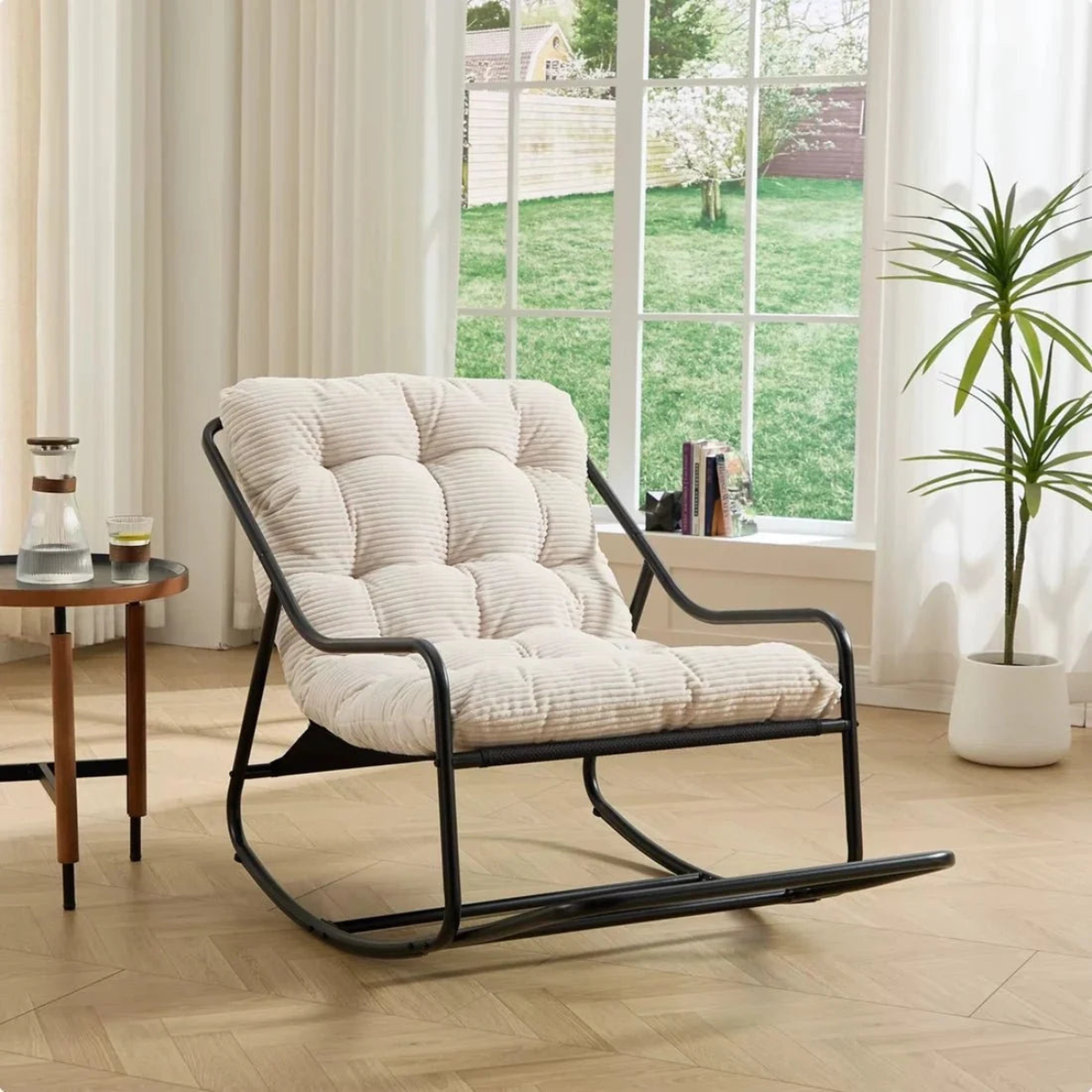 Rocking chair with white cushion in a room with a window view of a garden.
