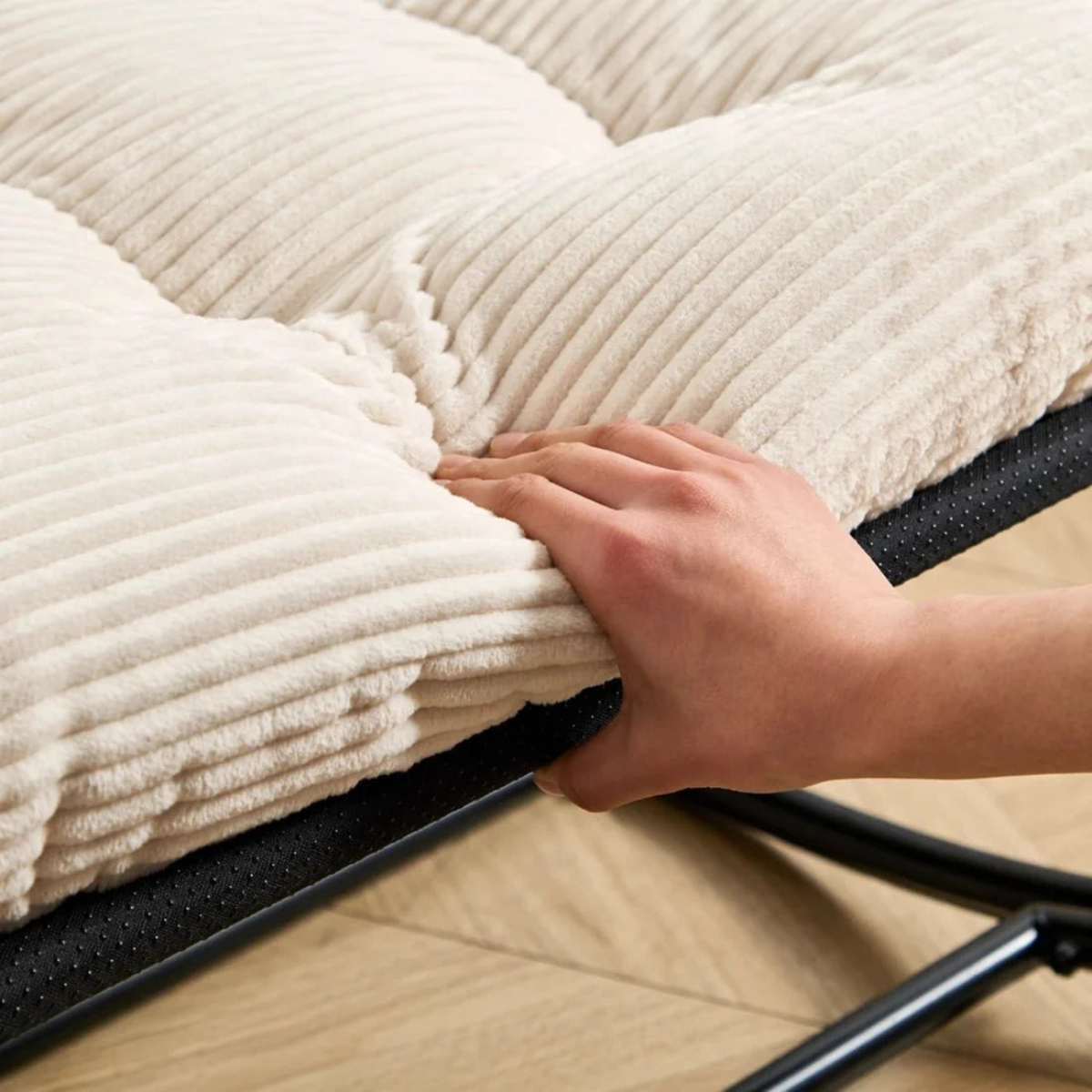 Person folding a white towel on a black ironing board.