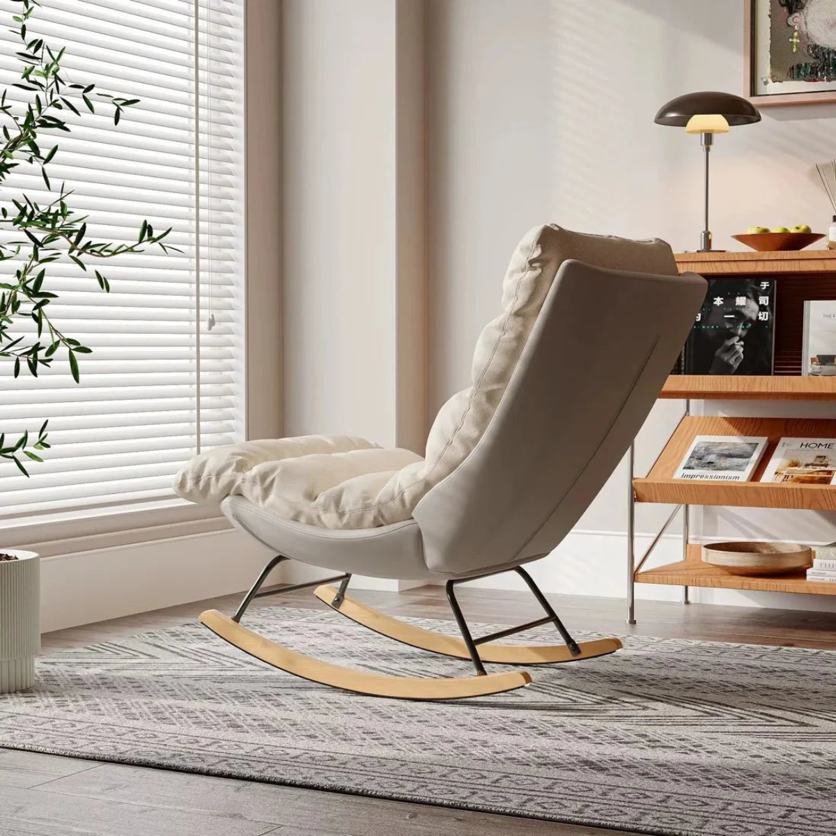 A cream-colored upholstered rocking chair with plush cushions and a natural wood rocker base, styled in a bright, modern living room next to a window with blinds.