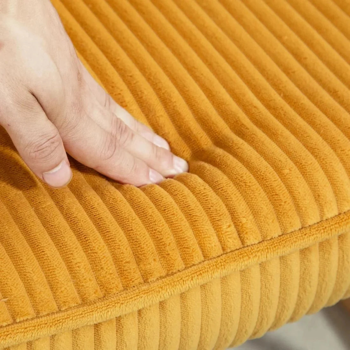 Close-up of a hand touching a ribbed yellow cushion