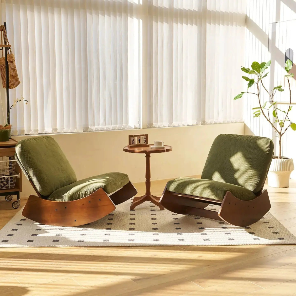 Two green lounge chairs with wooden bases in a bright room with large windows.