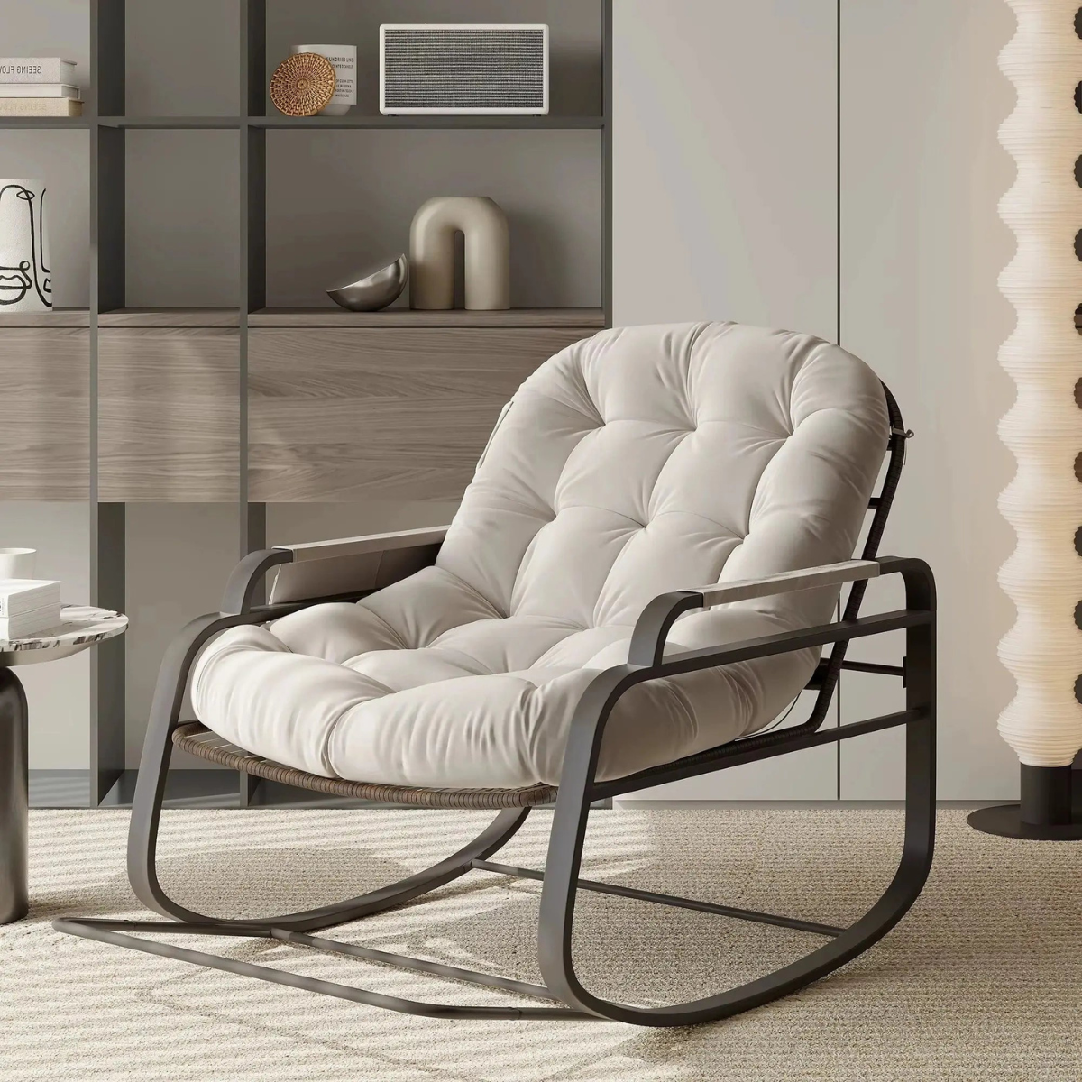 A modern tufted cushioned rocking chair with a light beige upholstered seat and backrest and a black metal frame, shown in a styled living room setting.