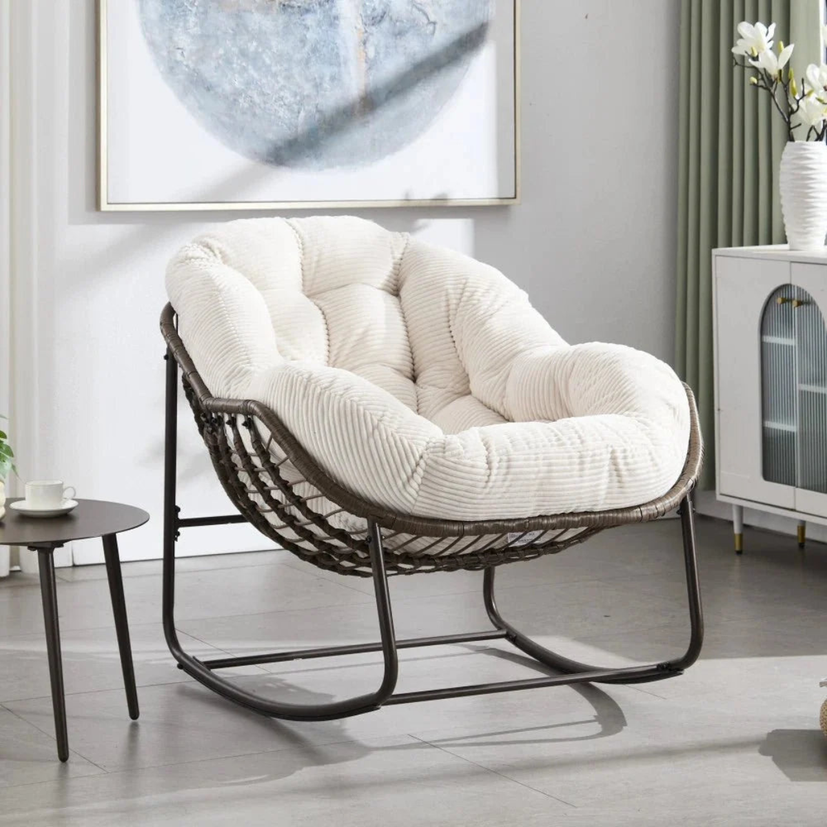 White cushioned chair in a room with a painting on the wall and a side table.