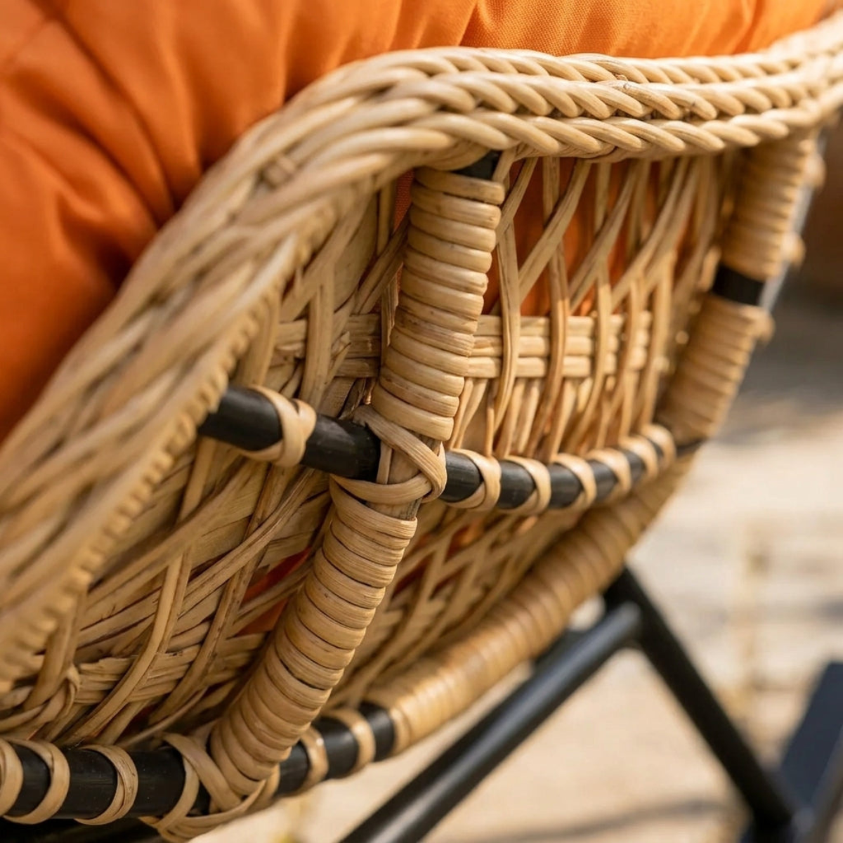 Close-up of a wicker chair with an orange cushion