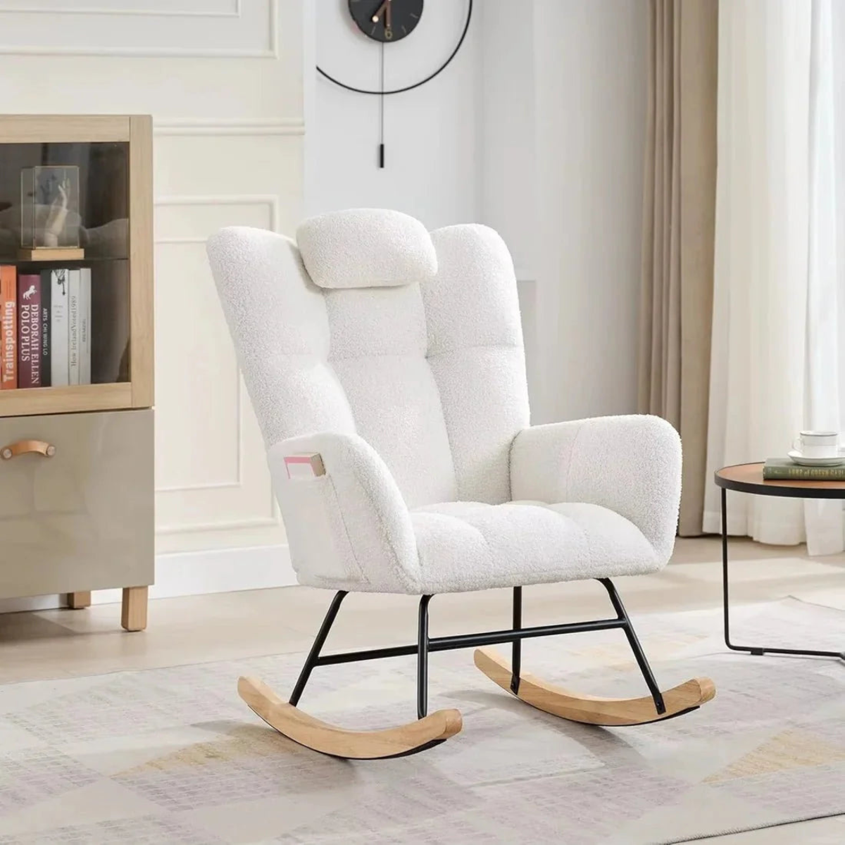 White rocking chair in a living room setting with a bookshelf and table in the background.