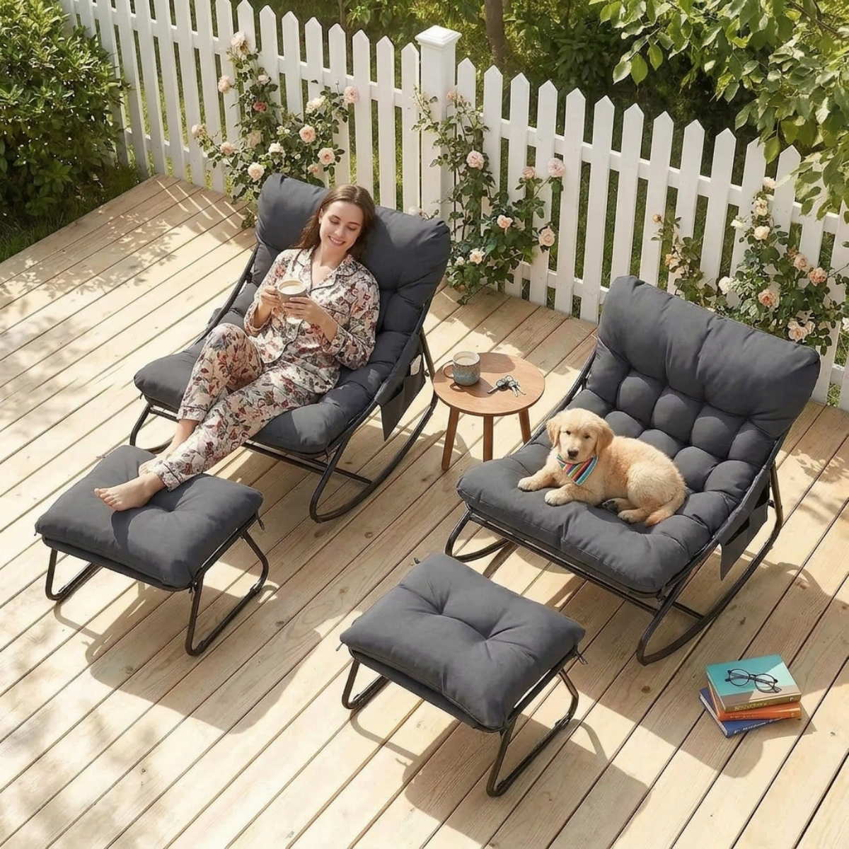 Three-piece outdoor patio lounge set with dark gray cushions and black metal frames, shown on a wooden deck with a woman in a floral pajama set reclining in one chair, a golden retriever dog resting in the second chair, and a matching ottoman in front.