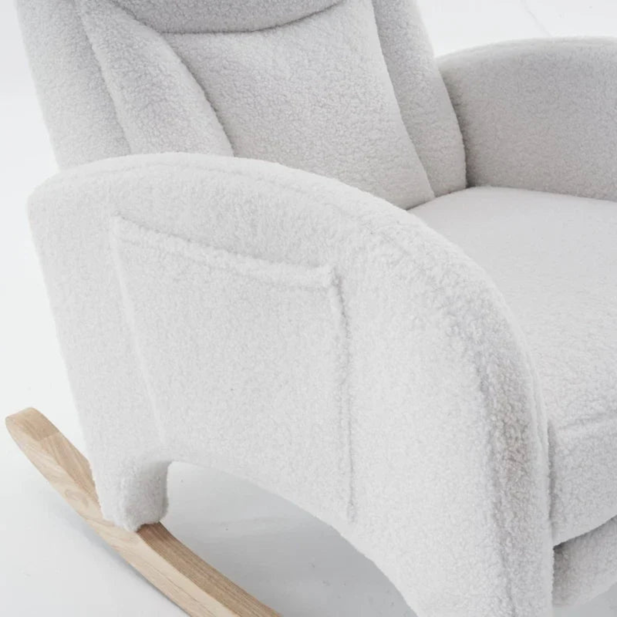 Close-up of a plush white bouclé rocking chair with a light natural wood rocking base against a clean white background.