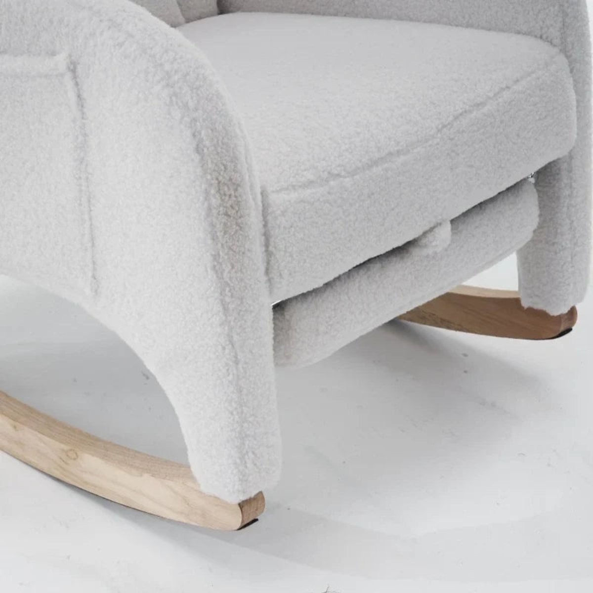 Close-up of a light gray textured fabric rocking chair with natural wood rocking legs on a white floor.