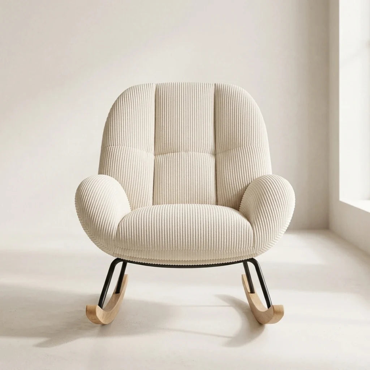 A cream-colored ribbed fabric rocking chair with a high tufted backrest and black metal legs with natural wood rockers, set against a minimalist cream wall and floor.