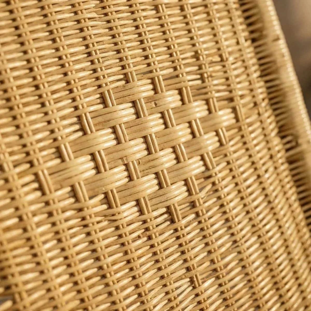 Close-up of a woven natural rattan or wicker surface showing the detailed texture and pattern of the interlaced strands in warm tan and light brown tones.