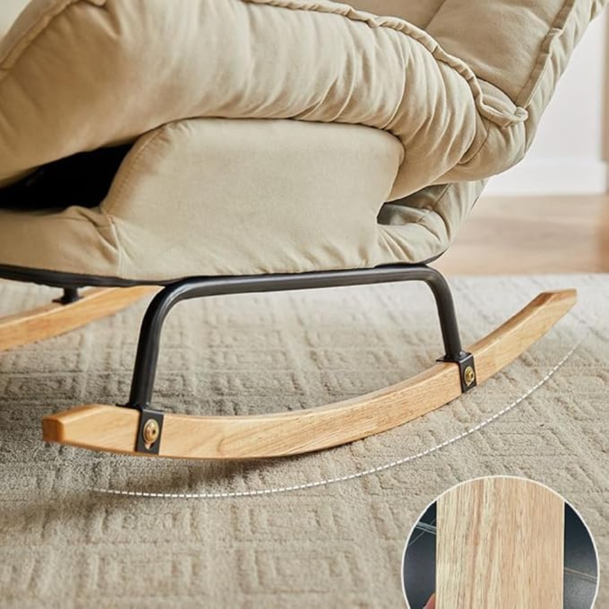Beige upholstered rocking chair with a curved wooden rock base and black metal frame, shown on a textured rug with a circular wood close-up inset.