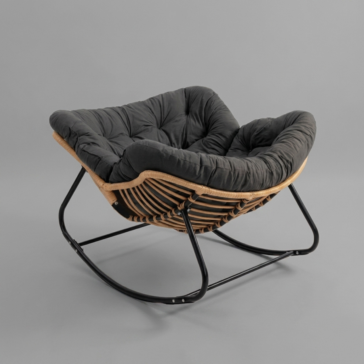A modern accent chair with a black tufted cushion, a woven natural wood seat, and a black metal rocking base, shown on a solid gray background.